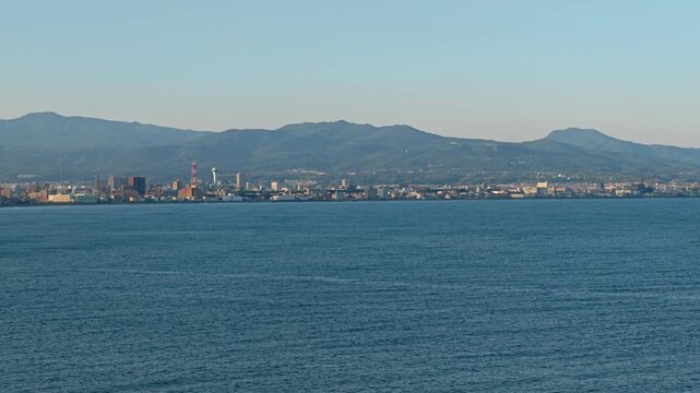 海岸線沿いに町と山が見える風景。
