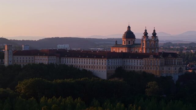 Melk Abbey in Austria, with a beautiful sunrise illuminating the historic Baroque abbey church and its magnificent architecture.