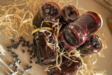 Artistic composition of organic wild blueberry preserve jars. A moody and stylish view of homemade wild blueberry jam jars arranged chaotically in two tiers on a table. The dark sweet berry preserve © Nadiia