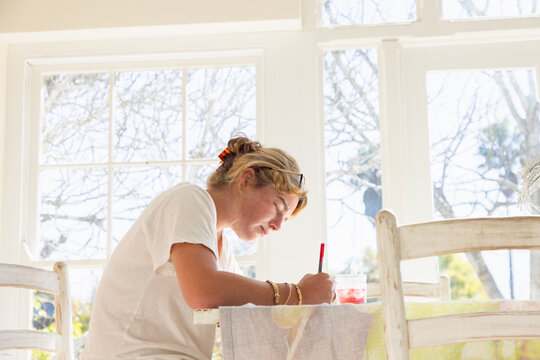 young woman drawing at table in light filled room