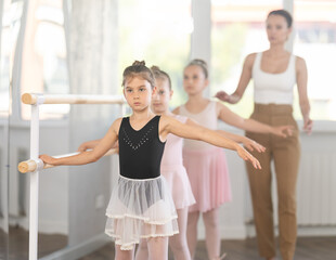 Little girls at the barre learning to get into the second position of ballet choreography © JackF