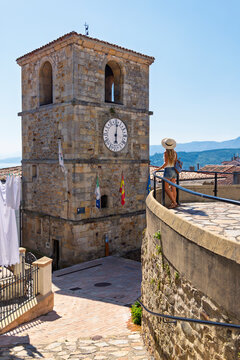 Woman admiring the historic clock tower of a spanish asturias village on a sunny day