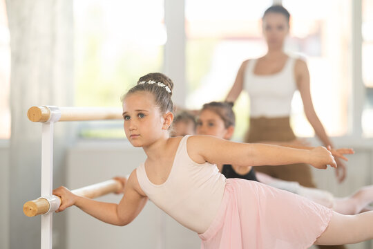 Little girls ballet lovers learn to perform arabesque pose in a choreography studio