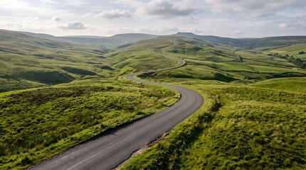 Fototapeta premium Empty country road winding through lush rolling green hills, creating a peaceful landscape with strong depth and natural perspective.