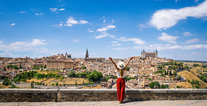Woman with arms raised overlooking the historic skyline of toledo, Travel destination, tour tourism in Spain