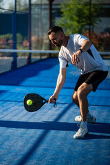 Male padel player hitting ball on blue court © Zoran Jesic