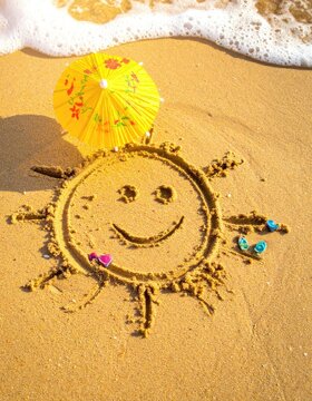 A smiley sun drawn in the sand with a yellow umbrella and seashells near the ocean.
