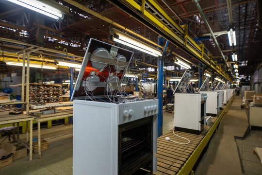 Factory assembly line with white ovens on conveyor belt under industrial lighting