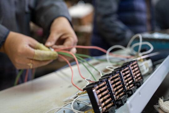 Closeup of hands assembling electronic wiring with copper connectors on workbench