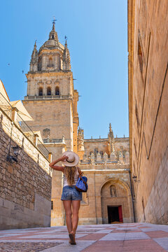 Woman walking towards the historic cathedral tower in the old town of salamanca spain