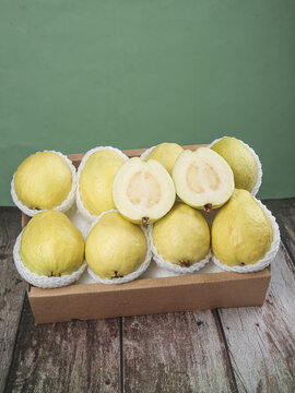 Fresh Yellow Guava Fruits in Protective Packaging on Wooden Table