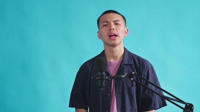 Energetic podcaster speaking into microphone with expressive hand gestures against blue background