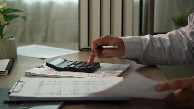 Accountant using calculator on financial documents for tax preparation, accounting, audit, bookkeeping, financial planning with copy space.