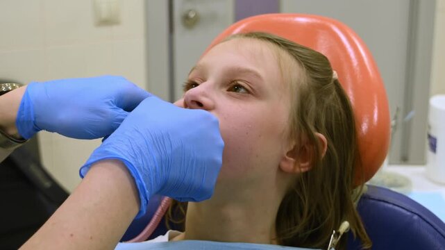 Orthodontist removes alginate dental impression tray from girl's mouth after molding teeth for removable expansion appliance.