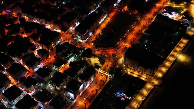 Aerial night view of a busy urban intersection in Tangier, Morocco, with illuminated roads, moving traffic and dense city blocks revealing nighttime urban life in North Africa.