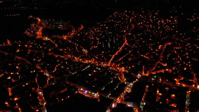 Aerial night view over Tangier, Morocco, revealing illuminated streets, dense urban neighborhoods and glowing city lights across the coastal city of Northern Morocco.