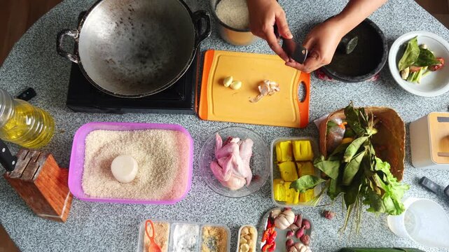Overhead view of chef peeling and slicing shallots on orange board during meal prep