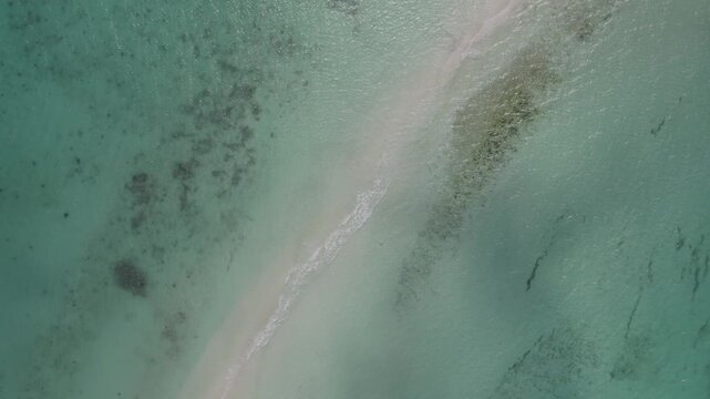 Aerial zenith view orbiting a pristine sandbar at Cayo de Agua in Los Roques beneath light clouds, drone backdrop