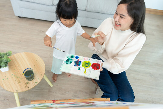 Happy Asia mother playing learning paint for little girl. Funny family is happy and excited in the house. Mother and daughter  having fun spending time together. Holiday, Activit