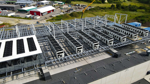 Data center rooftop undergoing expansion with numerous cooling units, ventilation systems, and metal framework being installed to manage server heat and ensure efficient operation