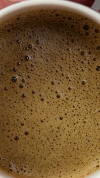 Ceramic bowl moves in gentle circles, revealing fine foamy hojicha texture during traditional Japanese tea brewing ritual.