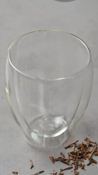 Prepared hojicha tea pours into clear double wall glass, forming foamy layer during Japanese roasted tea drink preparation.