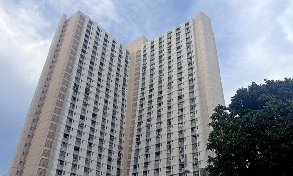Towering residential building with many windows against a cloudy sky