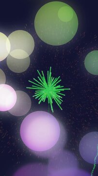 Animation of colourful spots of light over green fireworks exploding in night sky
