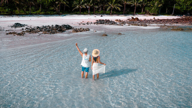 Couple tourist stay happy moment at the edge of the sea beach under shallow of the crystal clear water in summer trip on tropical island island