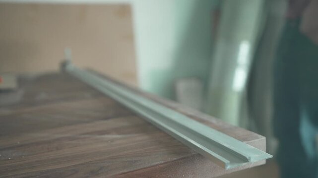Close-up of hands tightening a C-clamp bolt to secure a guide rail against a walnut countertop