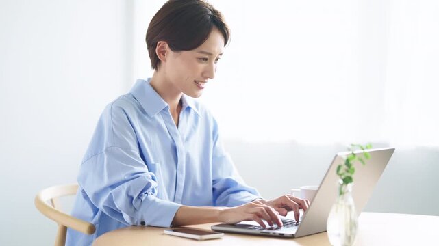 明るい室内でノートパソコンを使って作業をする日本人女性