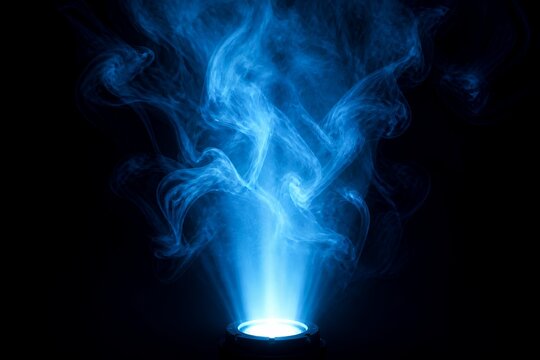Blue smoke beam from spotlight, abstract light plume on dark background