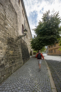 Tourist walking on cobblestone street by historic stone building in Halberstadt Germany