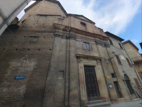 Facciata monumentale in mattoni e pietra di una chiesa barocca italiana, con portale storico in legno ripreso dal basso