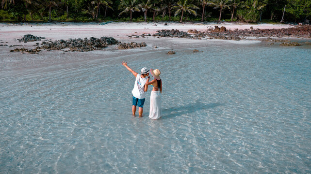 Couple tourist stay happy moment at the edge of the sea beach under shallow of the crystal clear water in summer trip on tropical island island