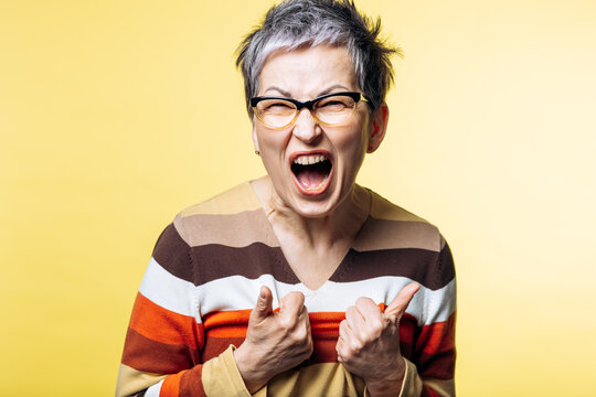 Woman with gray hair screaming, expressing anger and frustration. She is feeling upset, emotional, stressed, and experiencing stress
