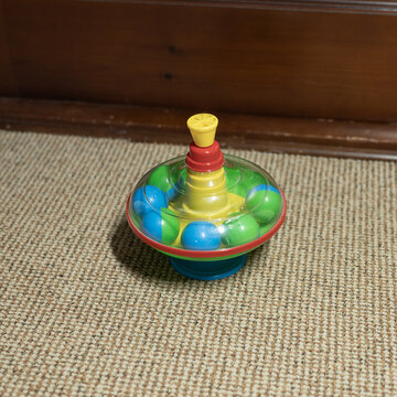 Colorful spinning top toy on carpeted floor