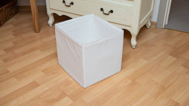 White fabric storage box on wooden floor in room with vintage furniture