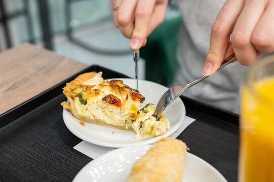 Person enjoying vegetable quiche and croissant with orange juice for breakfast