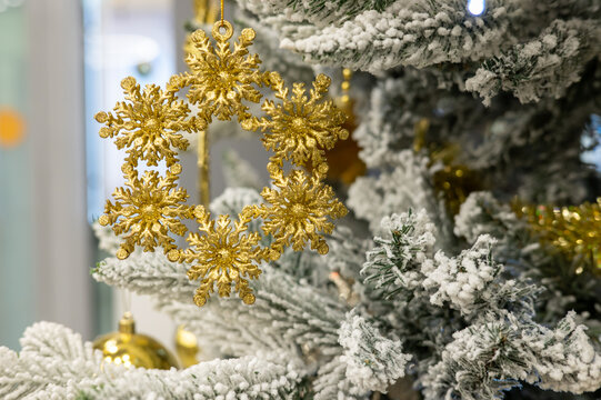 Golden snowflake ornament on frosted christmas tree branch