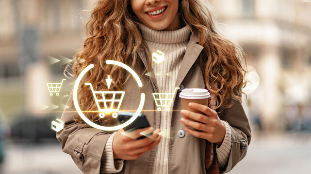 Woman holds coffee and phone while shopping online in city street on a sunny day