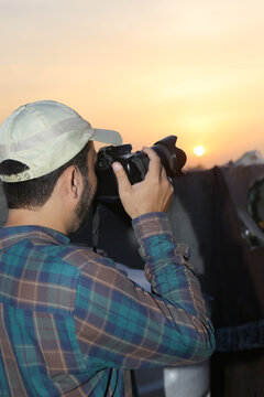 Faceless photographer taking sunset photos with film camera, capturing scenic mountain landscape, outdoor travel photography, nature exploration, creative hobby, photography activity, golden hour, 