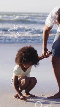 Animation of molecules over african american afather and son picking up shells on beach at sunset