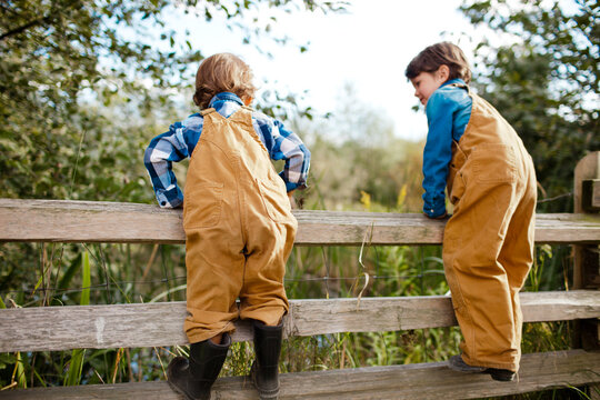 Young boys climbing a wooden fence