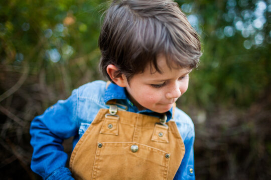 Young boy with freckles wearing brown overalls