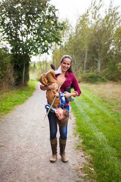 A mother playfully carries her son upside down while at a local park