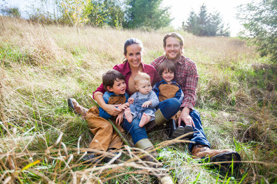 A fun portrait of a lively family of five sitting in a field