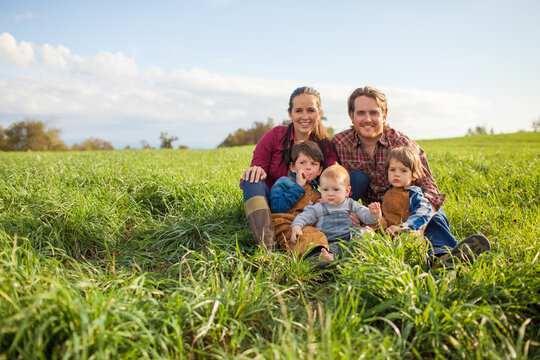 Happy family of five posing in a green field