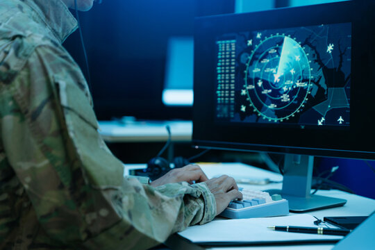 Military officer operating tactical computer screens and radar surveillance systems inside a high tech defense command center