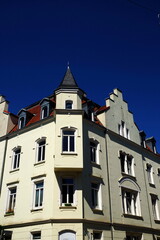 Obraz premium Schönes saniertes altes Eckhaus in Beige und Naturfarben mit Erker und Treppengiebel bei blauem Himmel und Sonnenschein in einem Stadtteil von Bielefeld im Teutoburger Wald in Ostwestfalen-Lippe